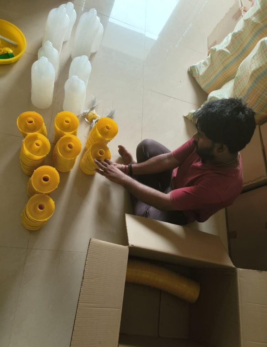 Yellow funnel trap parts and white bottle traps laid out on the floor for packing at Agri Phero Solutionz